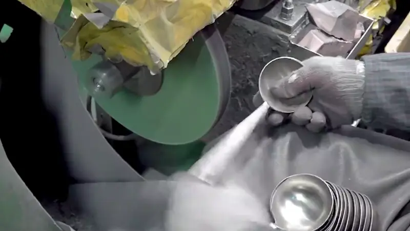 Un trabajador está biselando los cucharones de acero inoxidable