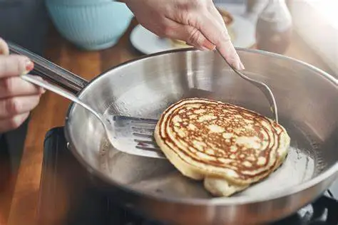 Dando la vuelta a los panqueques con una espátula ranurada de acero inoxidable