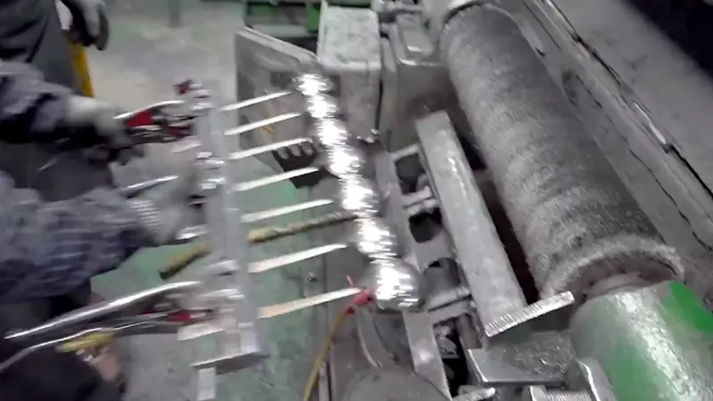 Un trabajador está puliendo los cucharones de acero inoxidable