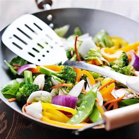 Sofriendo verduras con una espátula ranurada de acero inoxidable