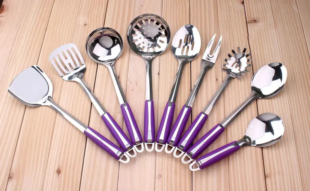 Utensilios de cocina con mangos de plástico morado sobre la mesa de madera