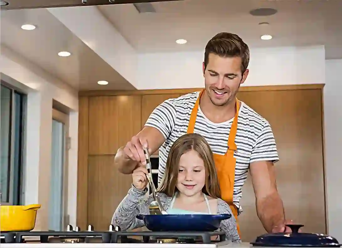 Father and daughter are cooking in the kitchen.