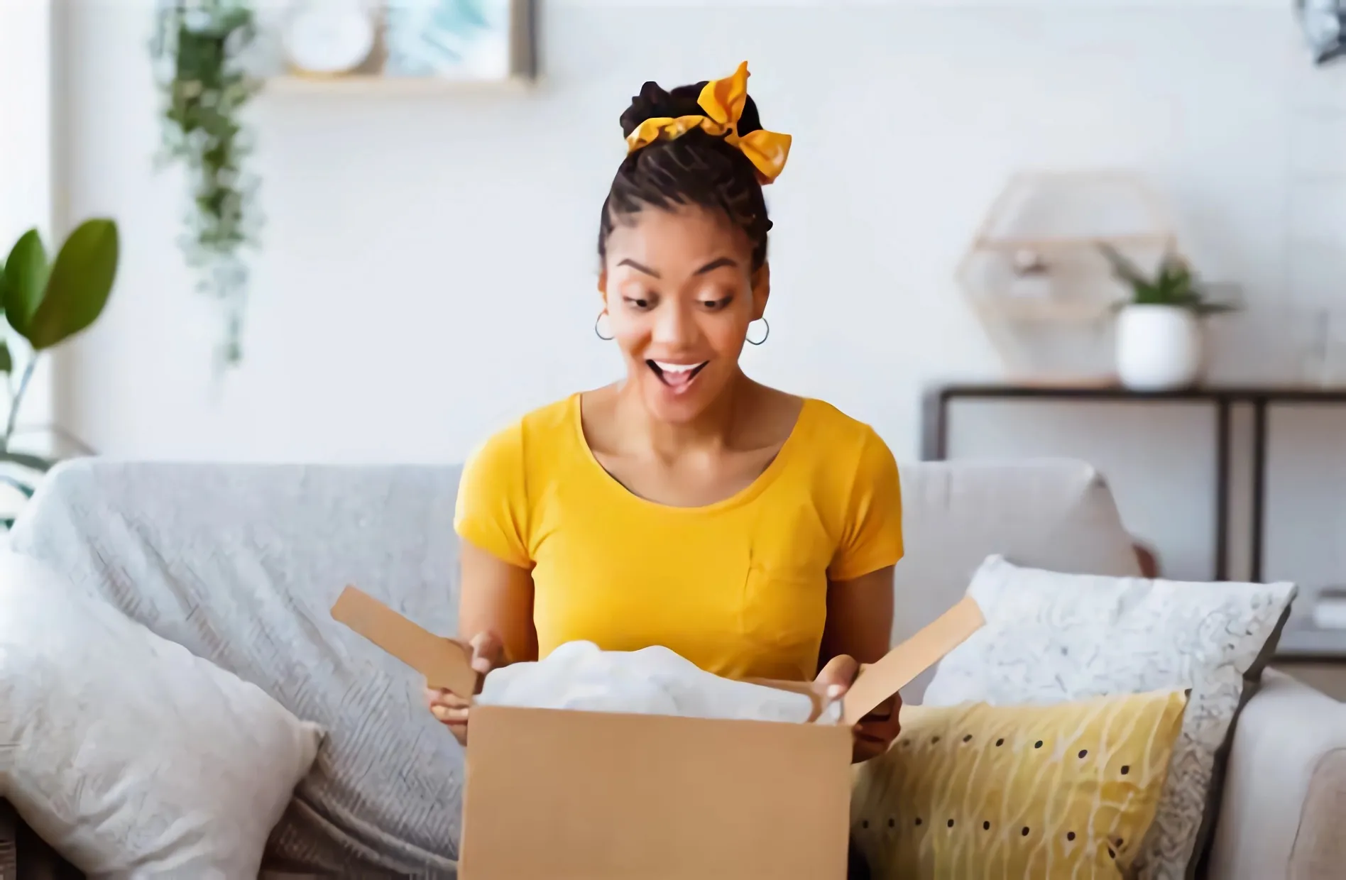 The unboxing experience of a woman who opens a corrugated box with a look of surprise on her face.