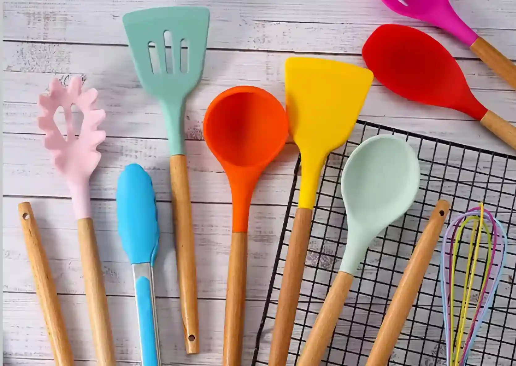 A group of colorful silicone kitchen utensils tools on slatted white wood
