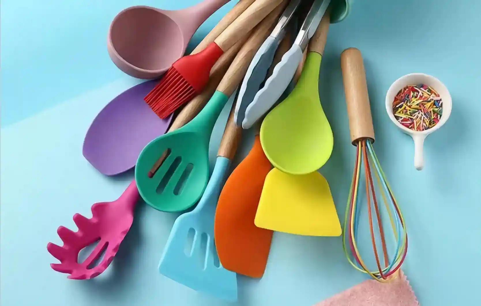 Different colorful silicone cooking utensils are placed on the blue countertop