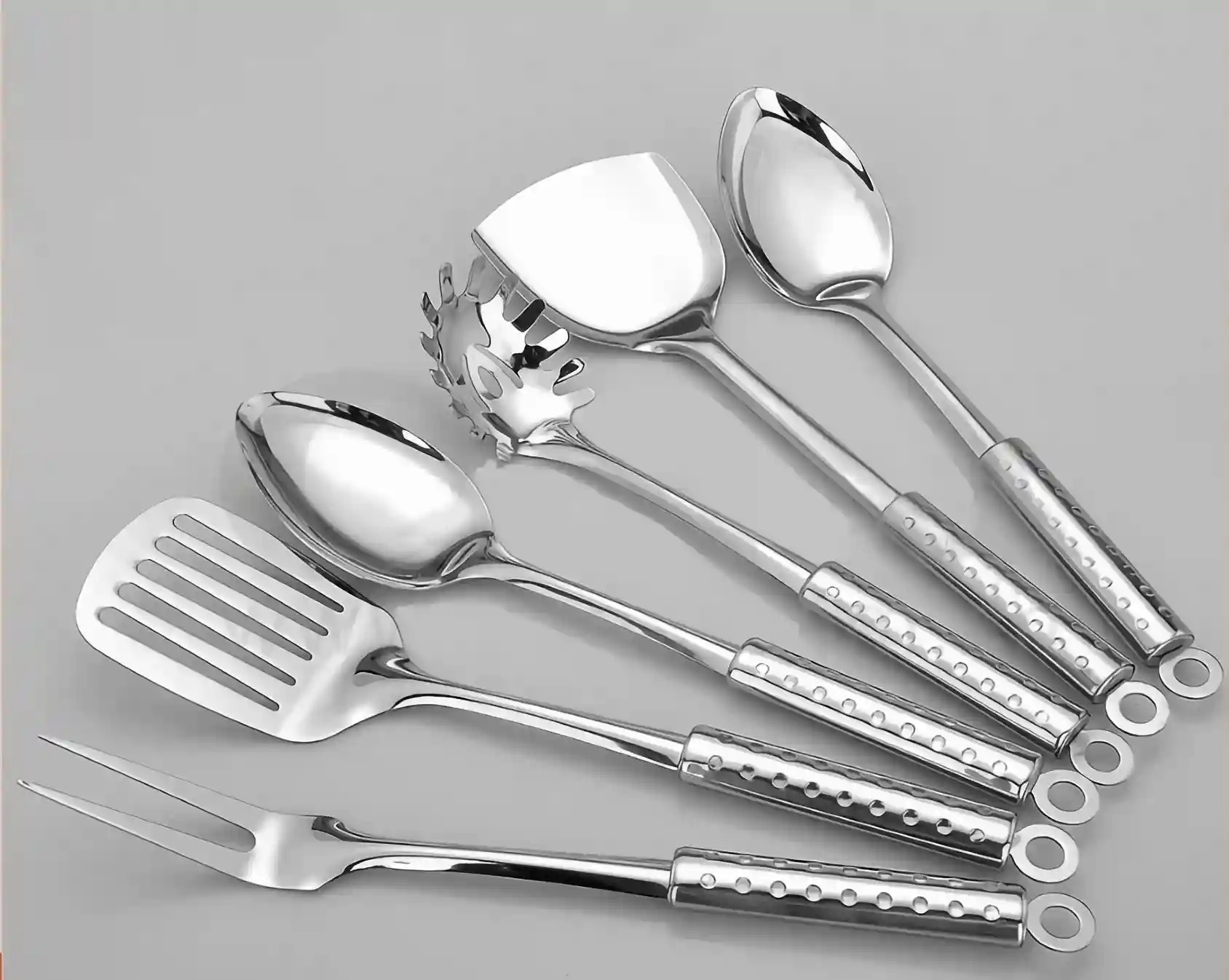 Set of stainless steel cooking utensils or kitchen tools displayed fanned out against light grey background