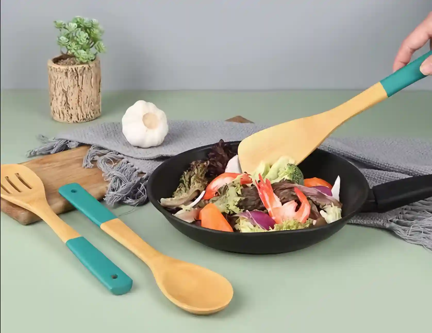 A bamboo spatula is placed in cookware filled with dishes